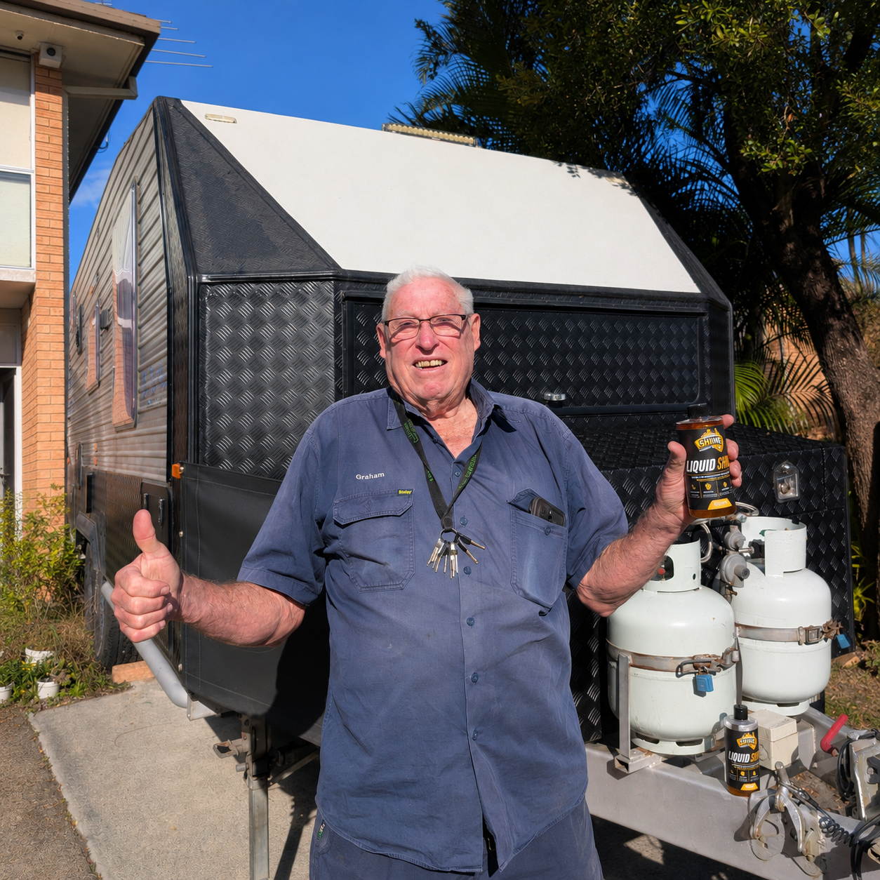 Happy customer holding a bottle of Liquid Shine outside his caravan